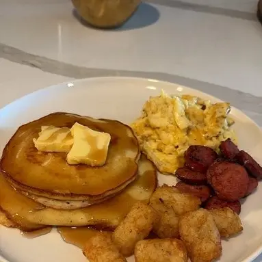 Pancakes with butter and syrup, scrambled eggs, sausage and tater tots.